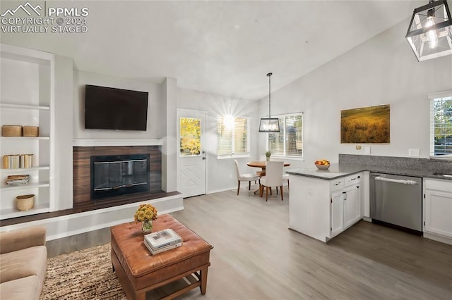 6555 Turkey Tracks Rd, Colorado Springs, CO 80922 - living area with vaulted ceiling, wood finished floors, built in shelves, a glass covered fireplace, and baseboards