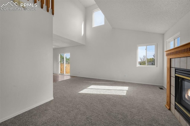 unfurnished living room featuring carpet, high vaulted ceiling, a textured ceiling, and a fireplace