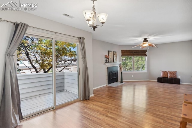 unfurnished living room featuring light wood-type flooring and ceiling fan with notable chandelier