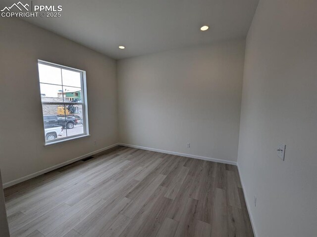 unfurnished room with baseboards, light wood-style floors, visible vents, and recessed lighting