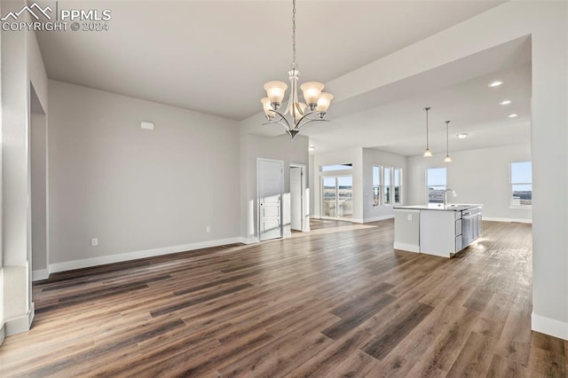 unfurnished living room with sink, dark hardwood / wood-style floors, and an inviting chandelier