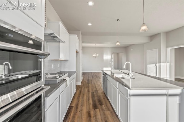 kitchen with wall chimney range hood, pendant lighting, dark hardwood / wood-style floors, white cabinetry, and an island with sink