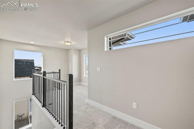 hall with plenty of natural light and light colored carpet