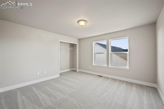 unfurnished bedroom featuring light carpet and a closet