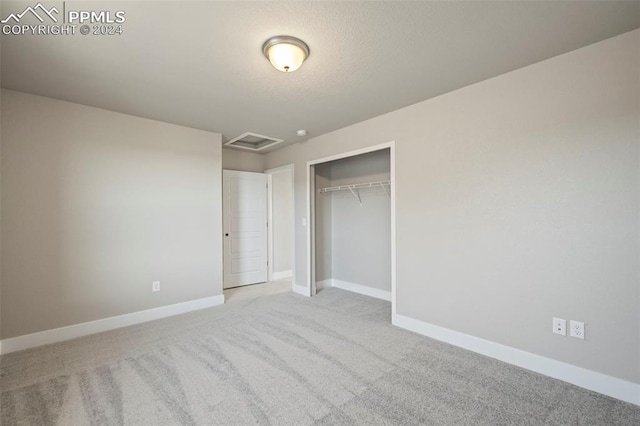 unfurnished bedroom featuring light colored carpet and a closet