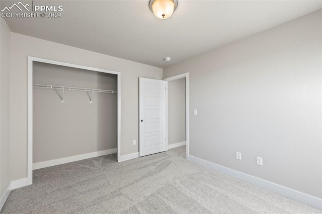 unfurnished bedroom featuring light carpet and a closet