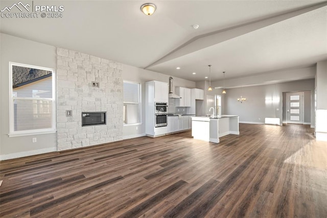 unfurnished living room featuring a wealth of natural light, sink, dark hardwood / wood-style floors, and lofted ceiling