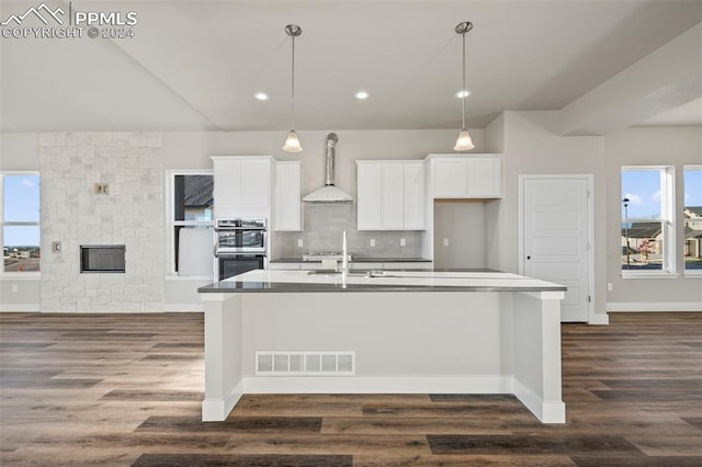 kitchen featuring white cabinets, dark hardwood / wood-style floors, wall chimney exhaust hood, and decorative light fixtures