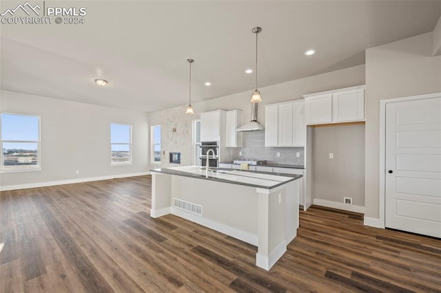 kitchen featuring pendant lighting, dark hardwood / wood-style flooring, white cabinetry, and an island with sink