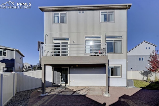 rear view of house featuring a balcony, cooling unit, and a patio