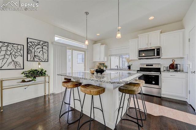 kitchen with appliances with stainless steel finishes, white cabinetry, dark wood-type flooring, and pendant lighting