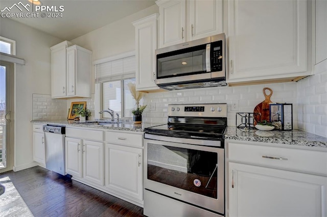 kitchen featuring appliances with stainless steel finishes, sink, white cabinetry, dark wood-type flooring, and light stone counters