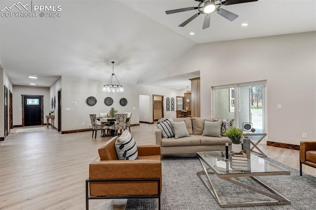 living room featuring lofted ceiling, ceiling fan with notable chandelier, and light hardwood / wood-style floors