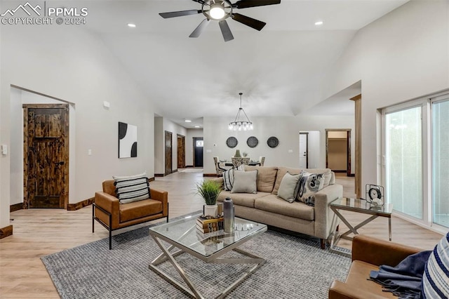 living room featuring ceiling fan with notable chandelier, light hardwood / wood-style flooring, and high vaulted ceiling