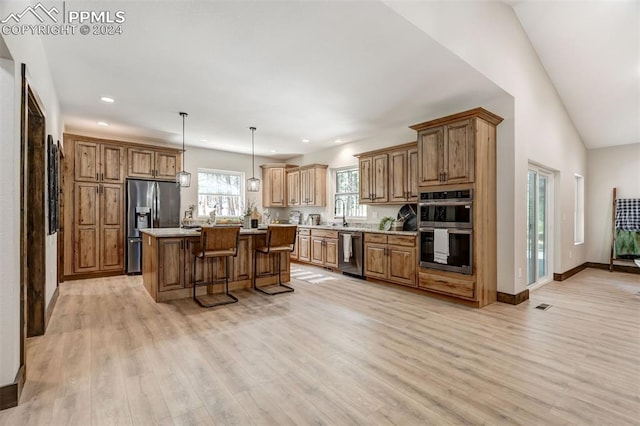 kitchen featuring light wood-type flooring, pendant lighting, a kitchen island, stainless steel appliances, and lofted ceiling