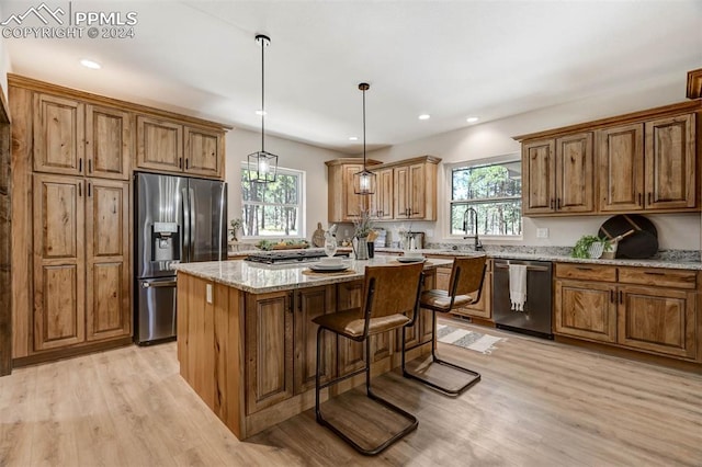 kitchen with appliances with stainless steel finishes, light stone countertops, a wealth of natural light, and a center island