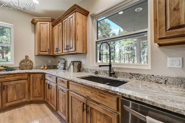 kitchen with light hardwood / wood-style flooring, sink, stainless steel dishwasher, and light stone counters