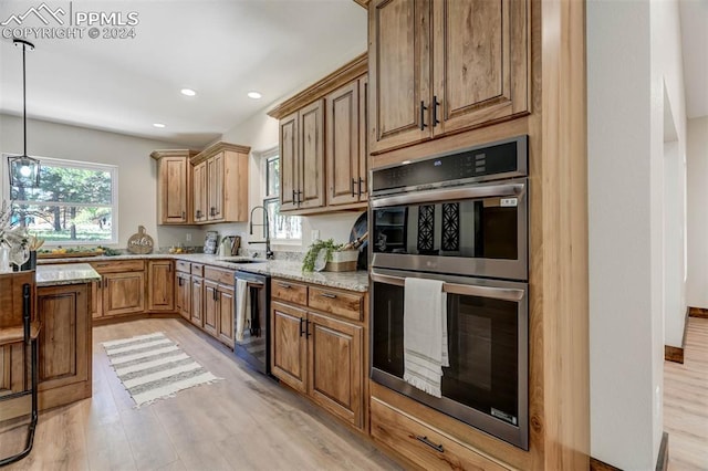 kitchen featuring light stone countertops, light hardwood / wood-style floors, double oven, and sink