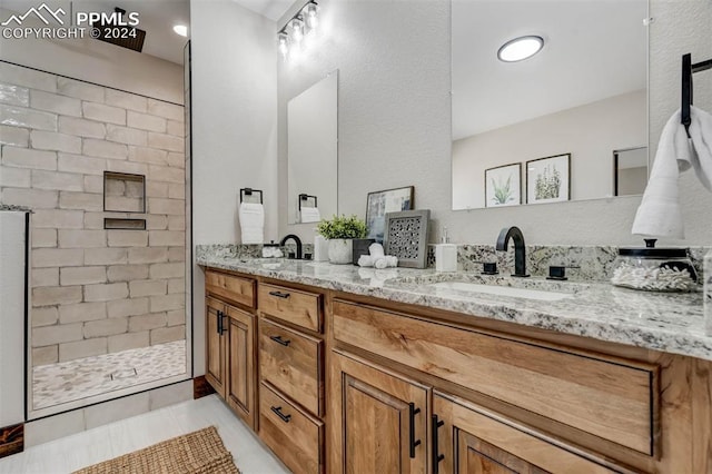 bathroom with a tile shower, vanity, and tile patterned flooring