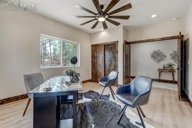 home office with light wood-type flooring and ceiling fan