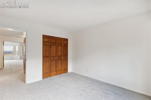 unfurnished bedroom featuring a closet and light colored carpet