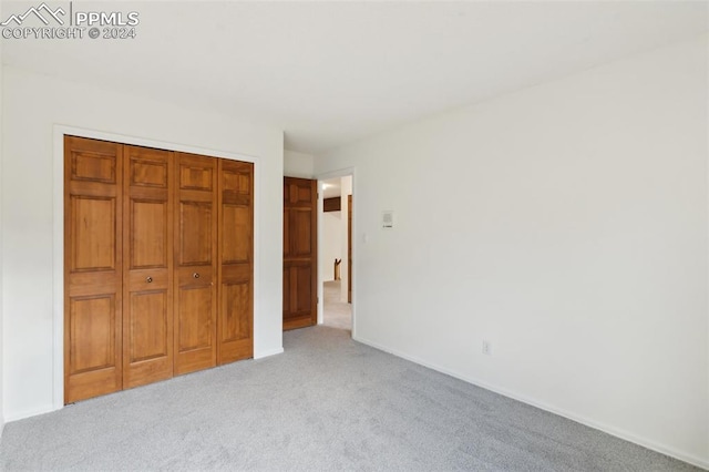 unfurnished bedroom featuring light colored carpet and a closet