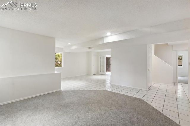 empty room featuring a textured ceiling and light colored carpet