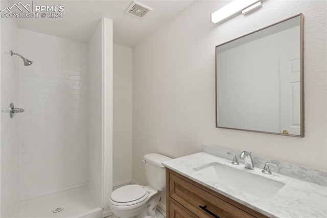 bathroom featuring toilet, vanity, and a tile shower