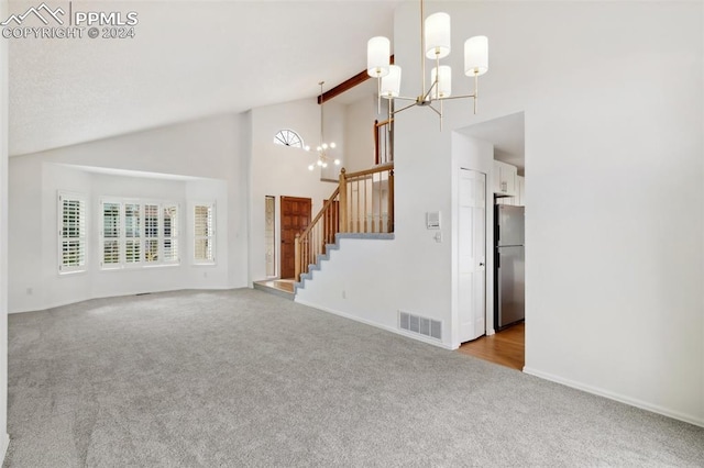 unfurnished living room with beam ceiling, a chandelier, light colored carpet, and high vaulted ceiling