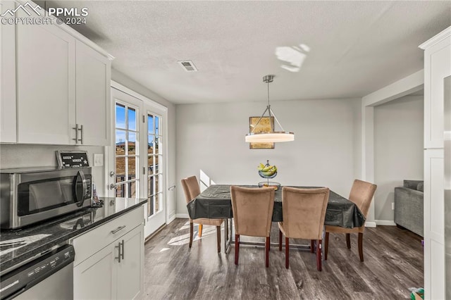 dining room featuring a textured ceiling, visible vents, baseboards, and dark wood-type flooring