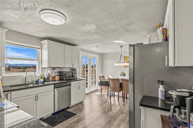 kitchen with stainless steel appliances, a textured ceiling, a sink, and wood finished floors