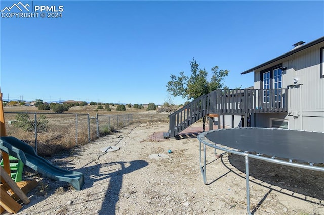 view of yard with fence, stairs, a playground, and a wooden deck