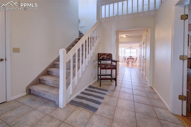 stairs featuring tile patterned floors and a high ceiling