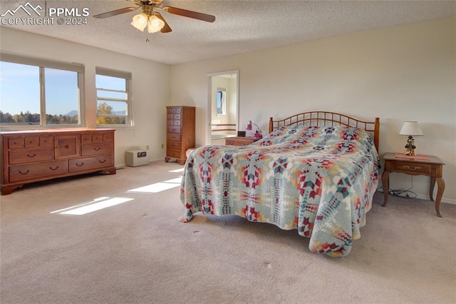 carpeted bedroom featuring a textured ceiling, ensuite bathroom, and ceiling fan