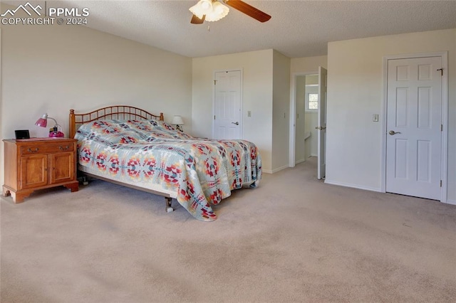 bedroom featuring a textured ceiling, light colored carpet, and ceiling fan