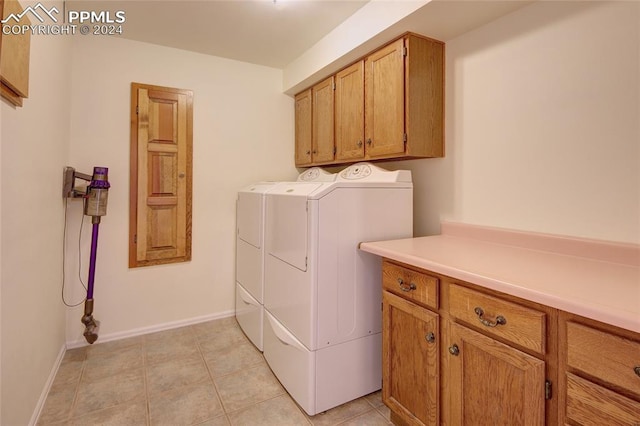 clothes washing area with cabinets, washer and clothes dryer, and light tile patterned floors