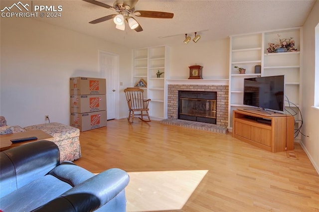 living room with ceiling fan, wood-type flooring, a textured ceiling, and a fireplace