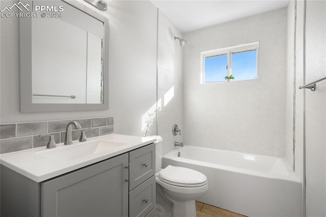 full bathroom with tasteful backsplash, vanity, tiled shower / bath combo, tile patterned flooring, and toilet