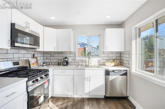 kitchen with appliances with stainless steel finishes, white cabinetry, dark wood-type flooring, and sink