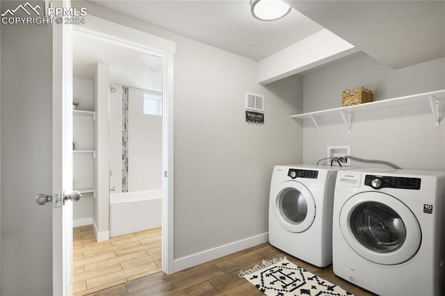 laundry room with hardwood / wood-style flooring and washing machine and dryer