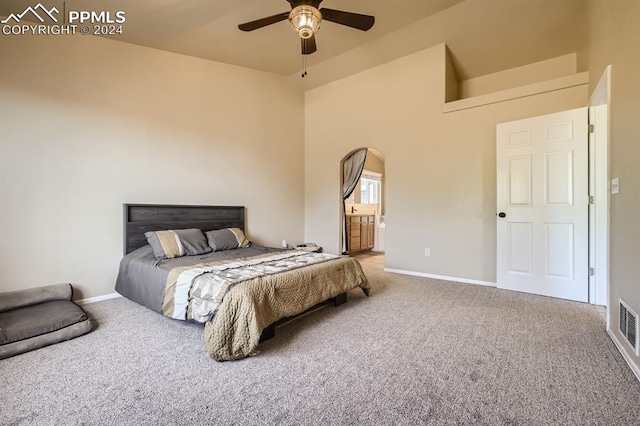 bedroom featuring carpet floors, ensuite bath, a high ceiling, and ceiling fan