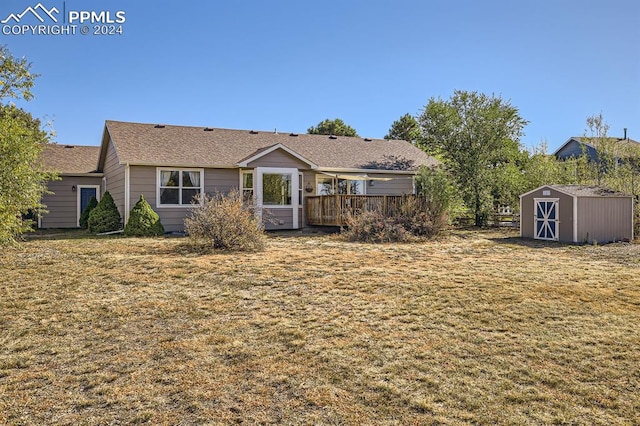 back of house with a wooden deck, a storage shed, and a lawn