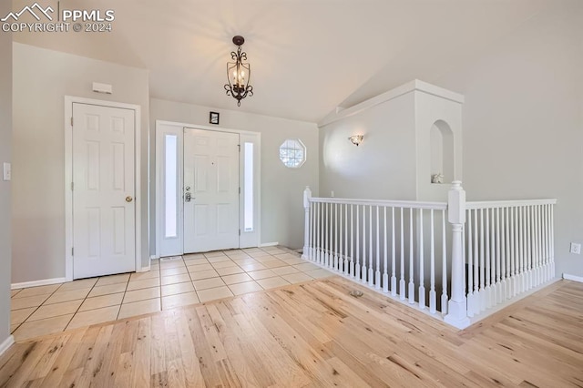 foyer featuring a notable chandelier, lofted ceiling, and light wood-type flooring