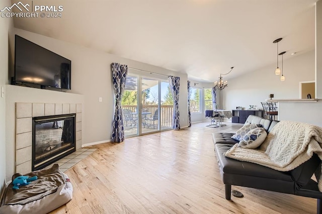 living room with lofted ceiling, a chandelier, a fireplace, and light hardwood / wood-style floors