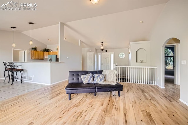 living room featuring high vaulted ceiling and light hardwood / wood-style floors