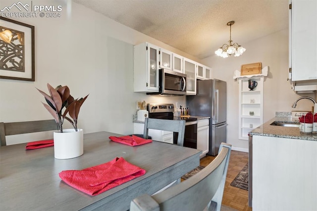 kitchen with white cabinetry, stainless steel appliances, sink, and hanging light fixtures