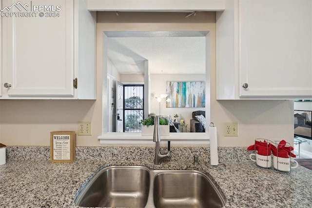 kitchen with sink, white cabinets, and light stone counters