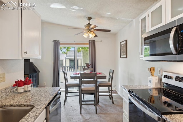 kitchen featuring appliances with stainless steel finishes, white cabinets, a textured ceiling, and light stone counters