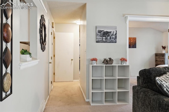 corridor with light carpet and a textured ceiling