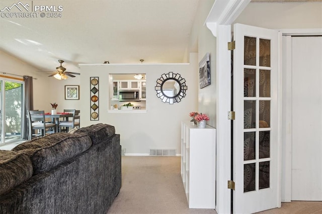 living room featuring light colored carpet, vaulted ceiling, and ceiling fan